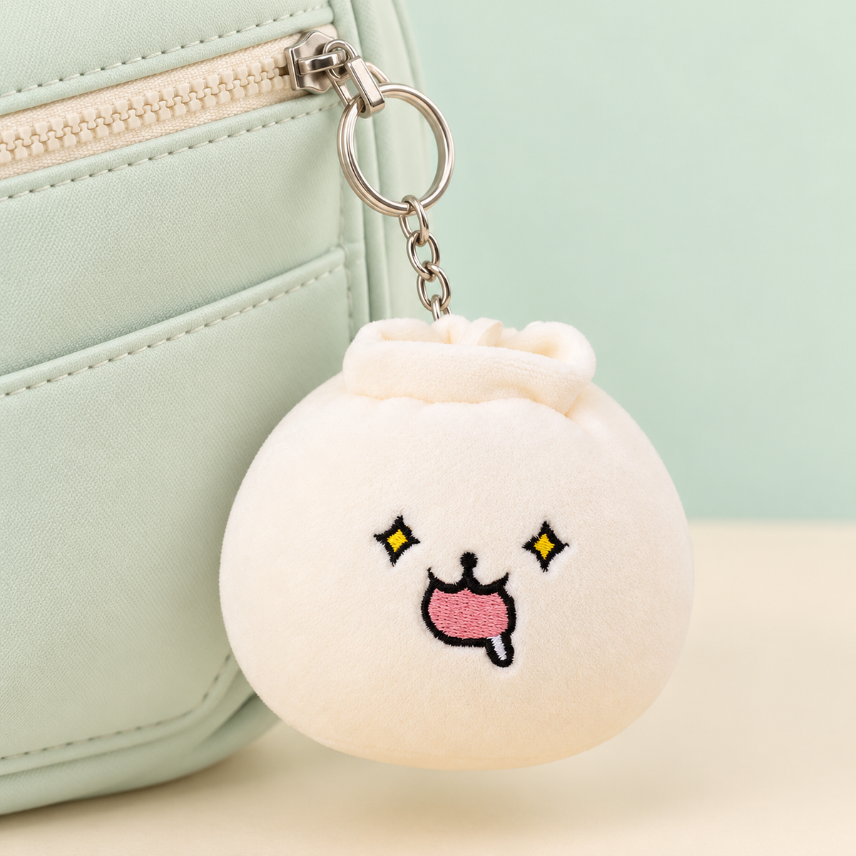 Drooling Dumpling Plush Keychain clipped to a pastel bag zipper