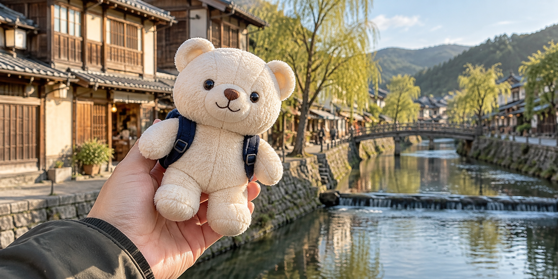 A cream bear plush with a tiny backpack is held in front of a canal and wooden buildings