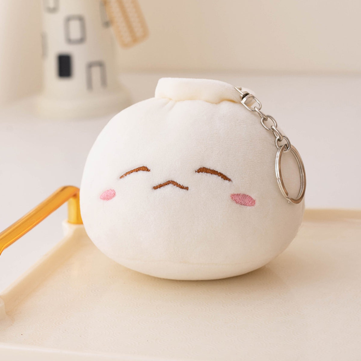 Cream dumpling plush keychain with a squinting embroidered expression