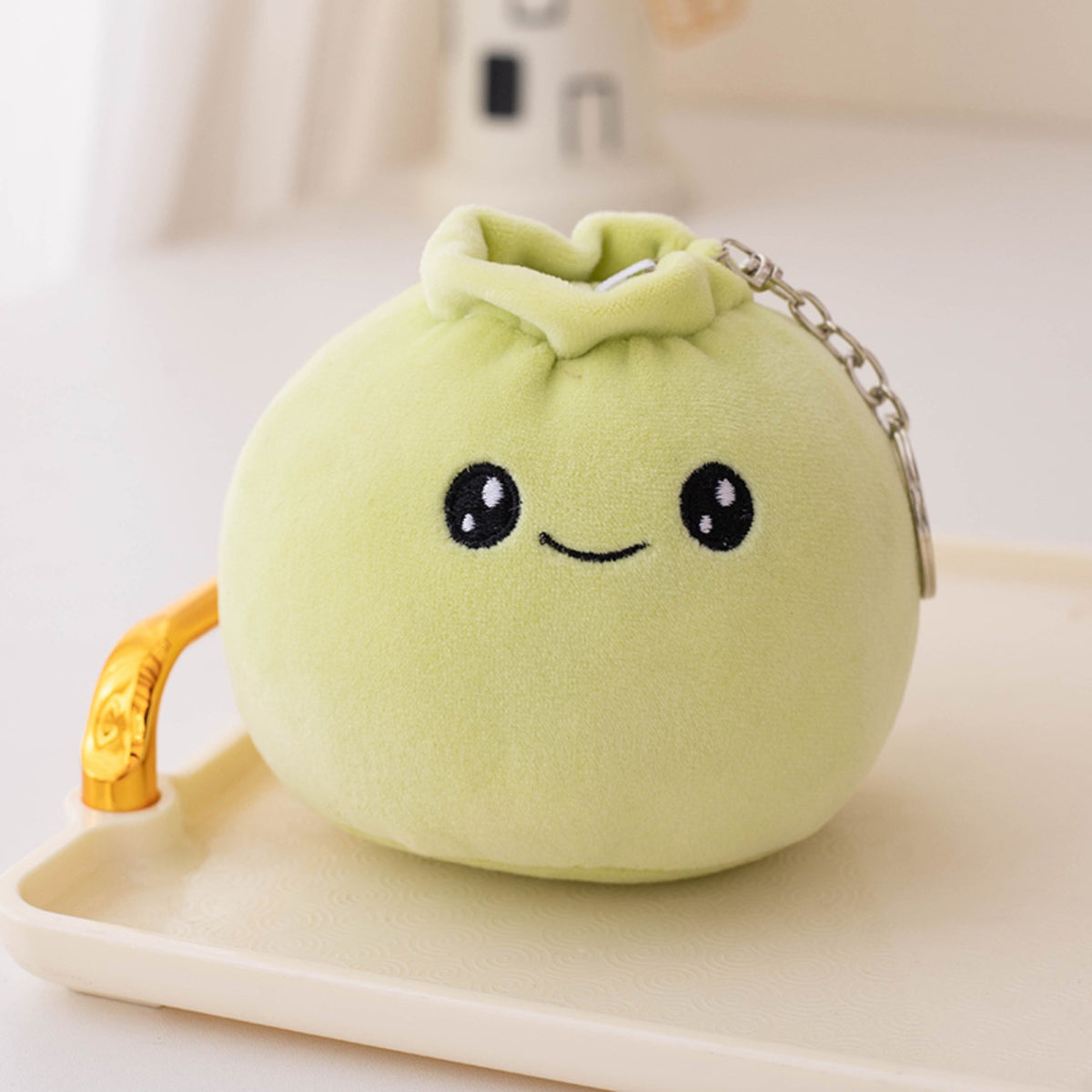 Green dumpling plush keychain with a cheerful embroidered smile
