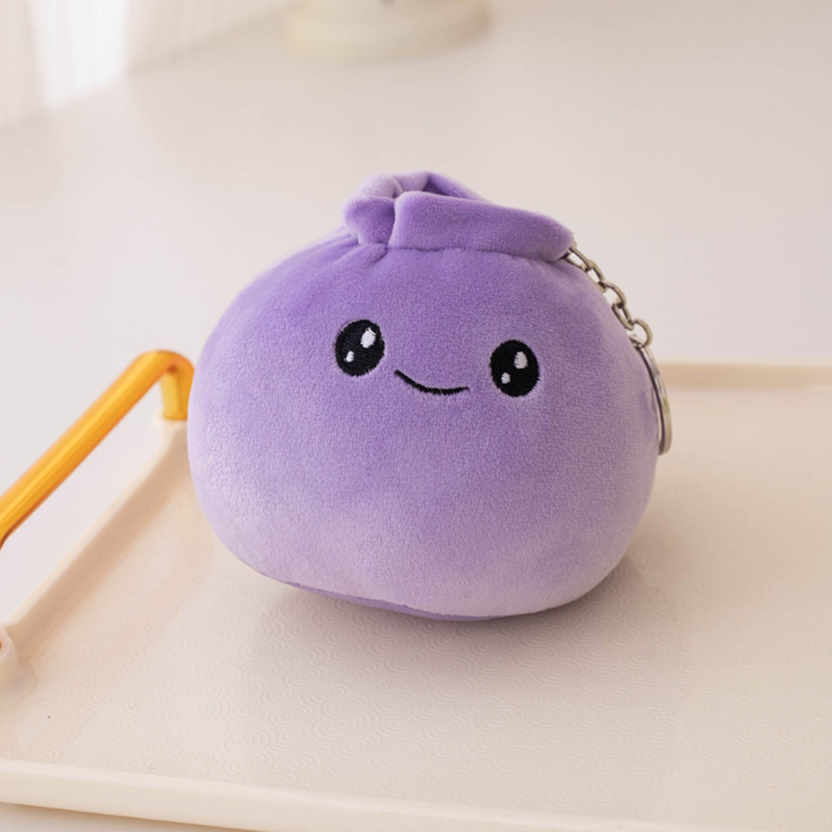 Purple dumpling plush keychain with a cheerful embroidered smile
