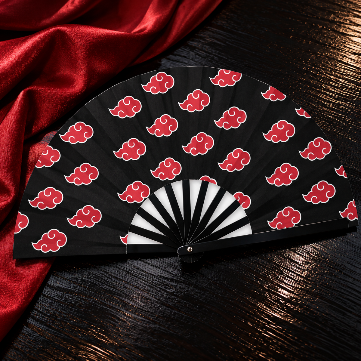 Akatsuki clouds folding fan displayed on dark wood beside red fabric