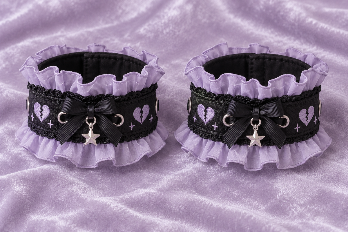 Pair of black Yami Kawaii wrist cuffs with lavender ruffles and heart details