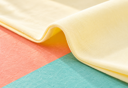 Close-up of the romper's pale cream fabric texture in a coral and teal setting