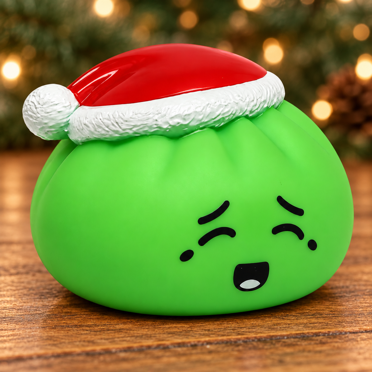 Green Elf Dumpling Squishy on wood with evergreen background