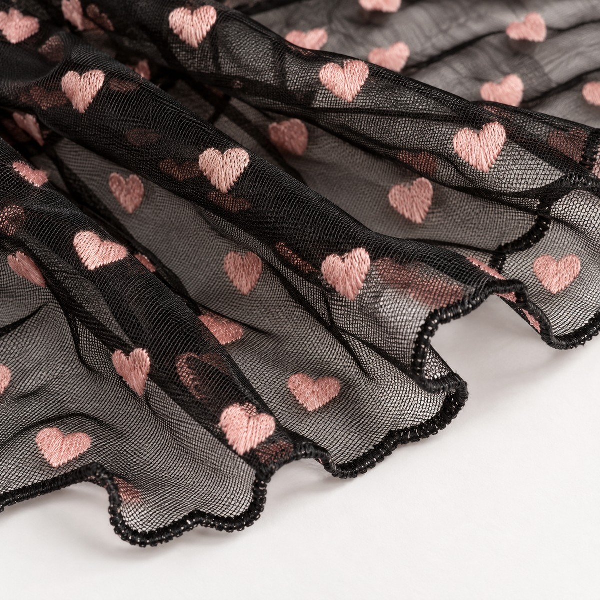 Close-up of the black mesh fabric and blush heart appliques