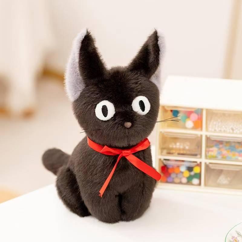 Black cat plush with red ribbon, sitting on a white table