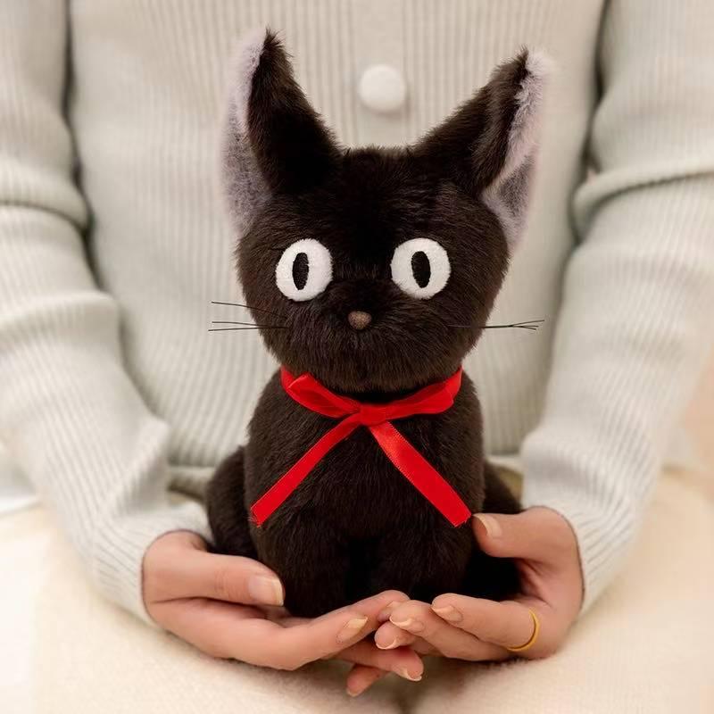 Black cat plush with red ribbon held in two hands