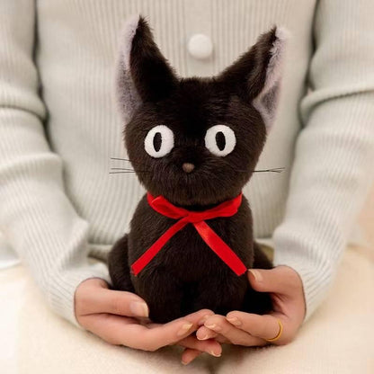Black cat plush with red ribbon held in two hands