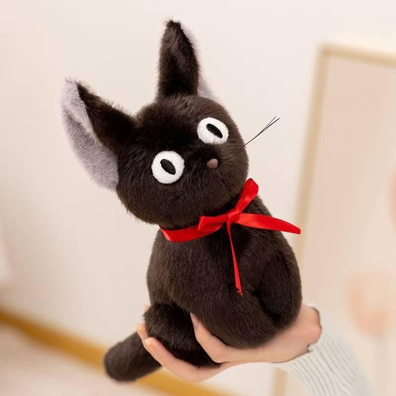 Black cat plush with red ribbon held up in one hand