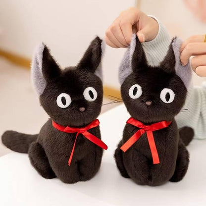 Two black cat plushes with red ribbons, one ear gently held
