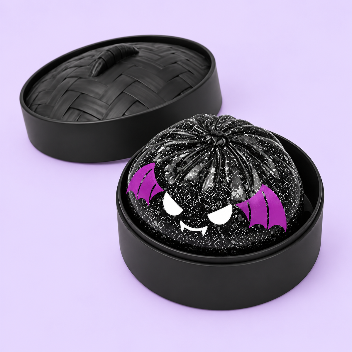 Spooky Bat Dumpling Squishy in its round case on a plain pastel lavender background